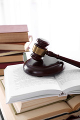 Gavel with pile of books on light blurred background