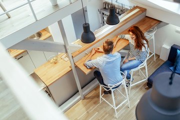 Couple sitting at counter in decorative home © NDABCREATIVITY