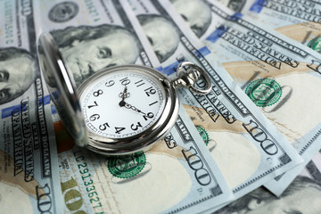 Time is money concept with pocket watch and dollars bills closeup
