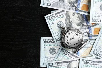 Time is money concept with pocket watch and dollars bills on wooden table, top view