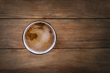 Glass of light beer on wooden background