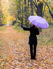 Lonely woman with bright umbrella in autumn forest