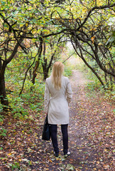 Lonely woman in a bright autumn forest Rear view