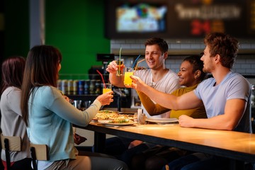 Cheerful multiracial friends having fun eating in pizzeria.