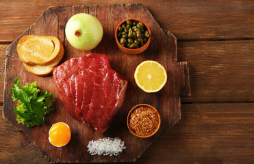 Beef tartare ingredients on wooden cutting board