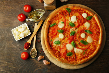 Margherita pizza with tomatoes, garlic, spices and Mozzarella on wooden background