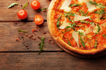 Margherita pizza with tomatoes, Parmesan and arugula on wooden background