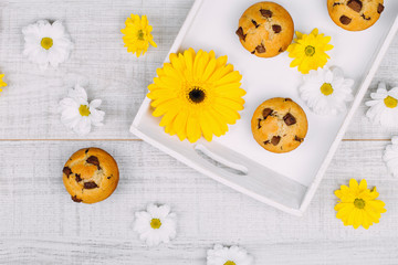 Homemade chocolate chip muffins on a white wooden tray decorated with flowers.