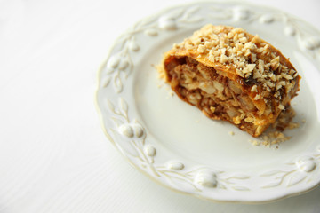 Slice of strudel with apples, walnut and raisins on white plate
