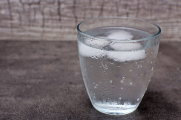 Glass of soda with ice on grey background