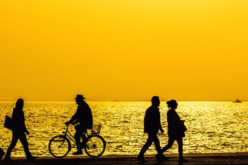 Silhouettes of people enjoying a walk by the seaside of the town