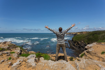 Obraz premium Tourist man on the rocky shore of sea. 