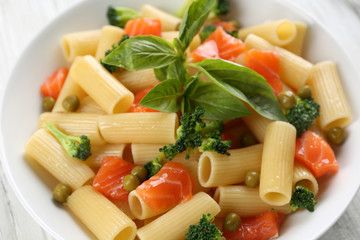 Plate of pasta with salmon and broccoli on table closeup