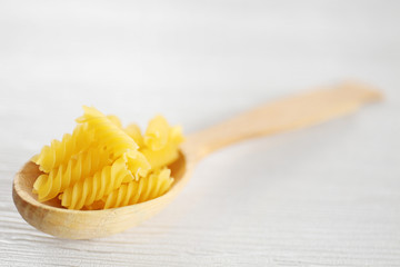 Fresh uncooked pasta in wooden spoon on table closeup