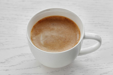 Cup of coffee on light wooden background