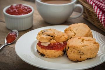 Scones with cream and jam on plate and coffee cup