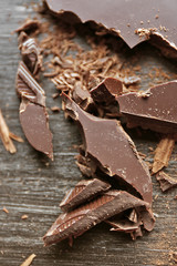 Pieces of chocolate on black wooden background, close up