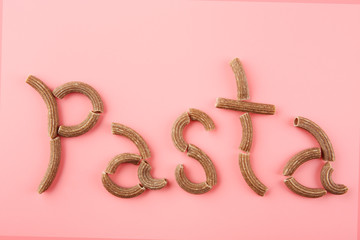 Pasta word made with brown macaroni on pink background