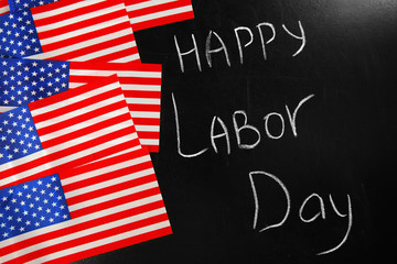 Happy Labour Day text and USA national flags on blackboard