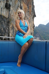 Женщина блондинка в голубом платье на катере среди тропических островов