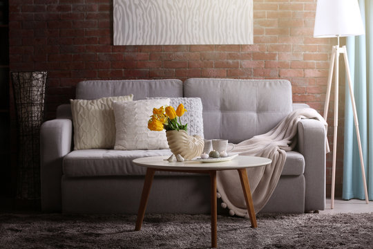 Design interior of living room with grey sofa and bouquet of flowers on table