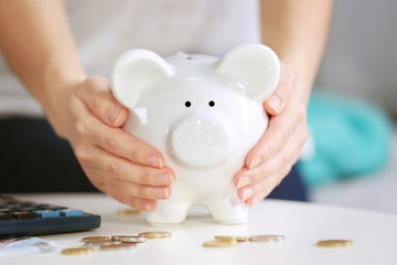 Obraz na płótnie Canvas Female hands holding piggy bank on table closeup