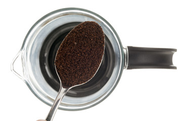spoon full of coffee powder over a coffee mug.