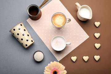 Delicious coffee and milk with candies on table, top view