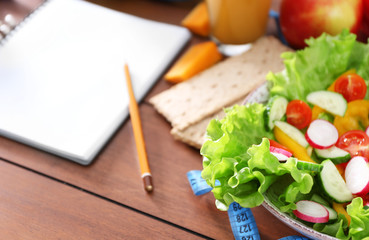 Vegetable salad and blank notebook on wooden table closeup