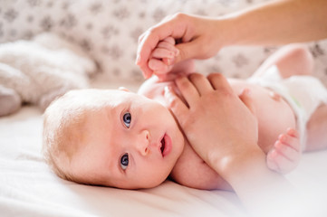 Baby boy lying on bed, held by his mother