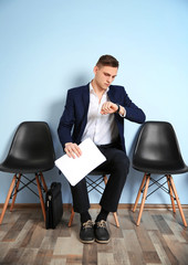 Young man in suit sitting on chair and waiting for job interview