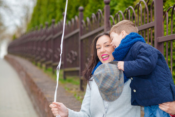 Obraz premium Portrait of fashionable baby boy and his gorgeous mother among balloons. little boy hugs his mother emotionally.