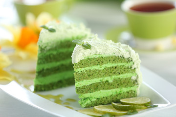 Pieces of delicious creamy lime cake on white plate closeup