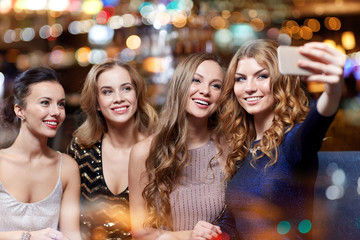 women with smartphone taking selfie at night club