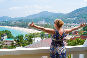 Fototapeta na wymiar Middle-aged woman enjoying the view over Kata beach from the hotel balcony. Phuket, Thailand.