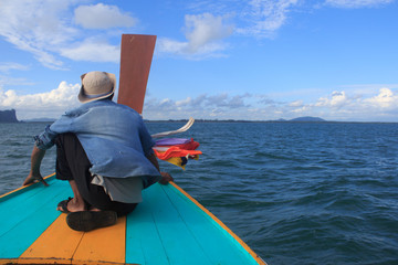 fisherman sit on nose of long tail boat in a sea to think about desination way