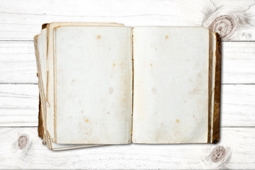 Old open blank book on white wood background.