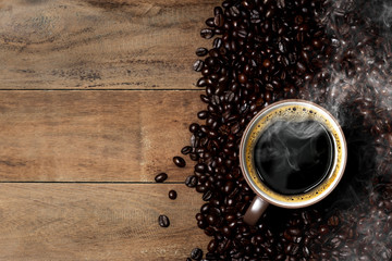 Coffee cup and coffee beans on a wood background with copy space.