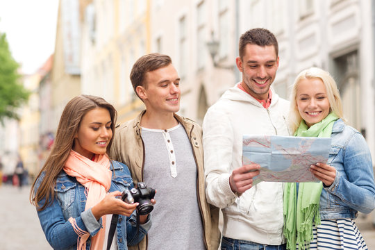 group of smiling friends with map and photocamera