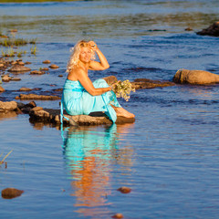 Mature beautiful blonde in blue dress enjoying the water