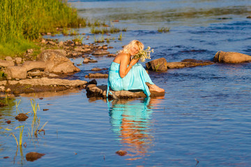 Mature beautiful blonde in blue dress enjoying the water