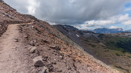Rocky slopes in the mountains. Amazing view at the peaks which rose against the cloud sky. Path on the tops of mountains. BURROUGHS MOUNTAIN TRAIL, Sunrise Area, Mount Rainier National Park