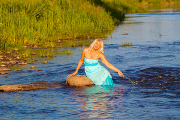 Fototapeta premium Mature beautiful blonde in blue dress enjoying the water