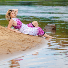 Woman in a long dress on the shore near the water