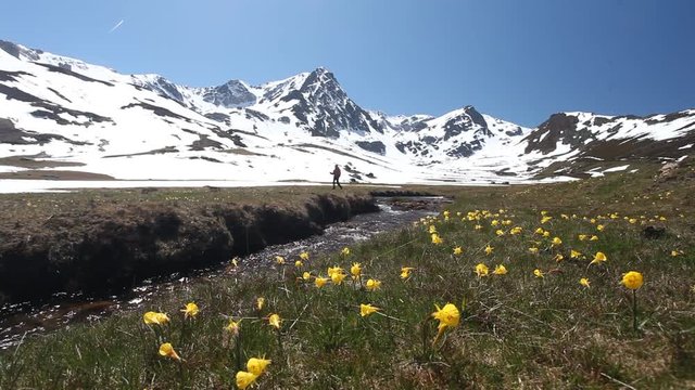 SENDERISTA PASEANDO POR UN PAISAJE DE ALTA MONTA&Ntilde;A EN PRIMAVERA Y PASANDO UN RIACHUELO