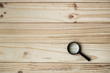 Magnifying Glass with Black Handle on the wooden background