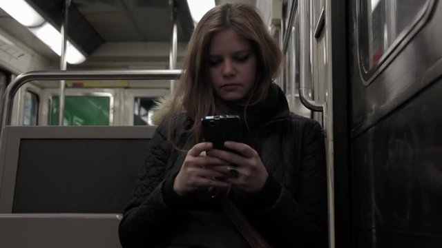 Girl With Smartphone Inside Metro. Woman using a smartphone while traveling inside the metro in Paris, France
