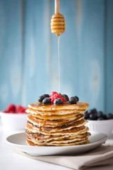 spoon honey pouring honey on pancake