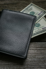 Black wallet and american dollar on wooden board.