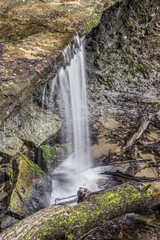 Maidenhair Falls, a small waterfall in Indiana's Shades State Park flows over a rock ledge with a recess cave below.